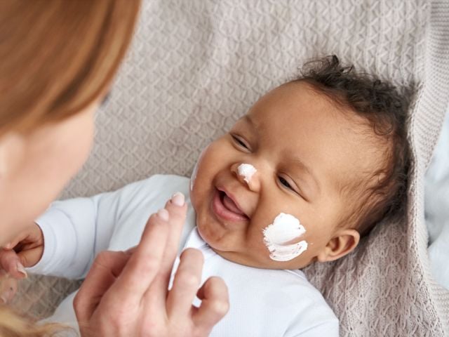 Mother applying sunscreen to child